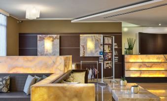 a modern living room with a marble couch and coffee table , as well as a tv mounted on the wall at Winter Garden Hotel Bergamo Airport