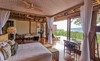 a luxurious bedroom with a large bed and a view of the ocean through sliding glass doors at Lapa Rios Lodge by Boena