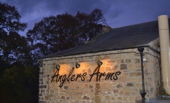 "a brick building with a sign that reads "" anglerris arms "" illuminated at night , creating a warm and inviting atmosphere" at Anglers Arms
