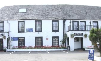 "a white building with black trim , a sign for "" crystal bay inn "" on the ground floor" at Uplawmoor