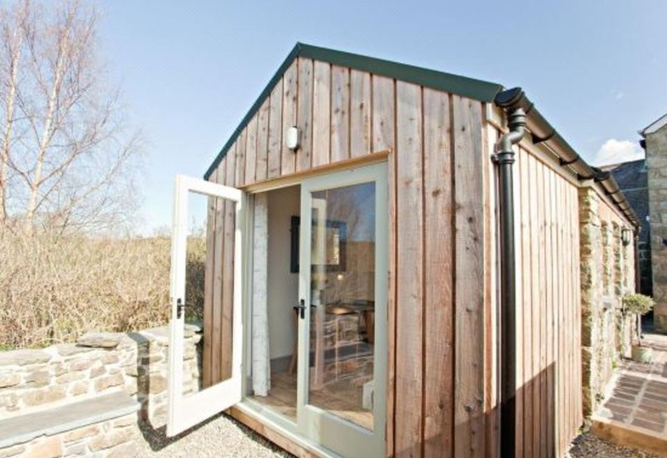 a wooden house with large windows and a door open , situated in a wooded area at Grove Park