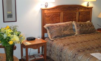 a bedroom with a wooden bed , two nightstands , and a vase of flowers on one of the nightstands at Casa de San Pedro Bed & Breakfast