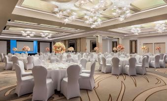 a large , well - decorated banquet hall with multiple tables set for an event , including white tablecloths , chairs , and flowers at Ramada by Wyndham Ramnicu Valcea