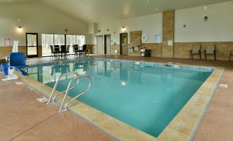 an indoor swimming pool surrounded by a lounge area , with people sitting and enjoying their time at GrandStay Hotel & Suites