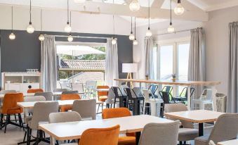 a modern restaurant with multiple dining tables and chairs , as well as several chairs for patrons to sit and enjoy their meals at Kyriad Lyon Est - Saint Quentin Fallavier