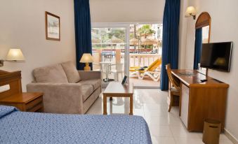a hotel room with a bed , couch , and desk , as well as a sliding glass door leading to a balcony at Bahia Tropical