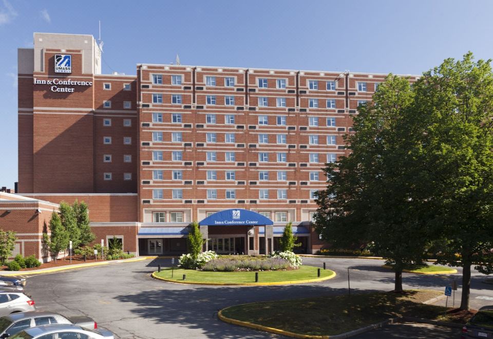 a large brick building with many windows and a blue sign on the side of the building at UMass Lowell Inn and Conference Center