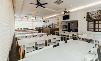 a large , well - lit dining area with white tables and chairs , surrounded by counters and a kitchen area at Kertih Damansara Inn