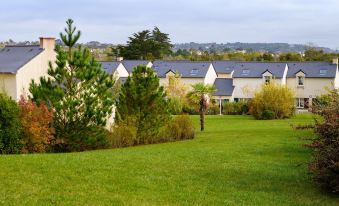 a man is playing a game of golf on a grassy field , surrounded by trees and houses in the background at Lagrange Vacances le Hameau de Peemor PEN