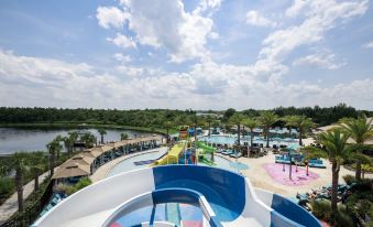 a large water park with multiple slides and a pool , surrounded by trees and a lake at Balmoral Resort Florida