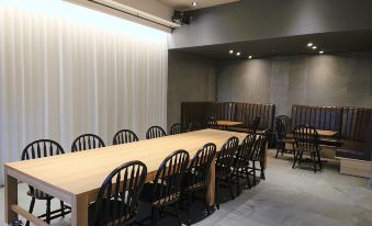 a large wooden dining table surrounded by black chairs in a room with white walls at Green Rich Hotel Kurume