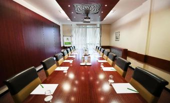 a large conference room with a long wooden table , multiple chairs , and papers set up for a meeting at Holiday Inn Telford - Ironbridge