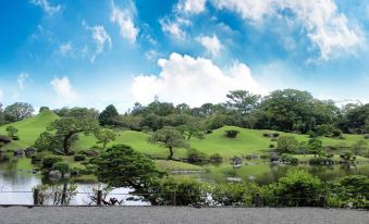 a serene landscape with lush greenery , blue skies , and a serene river in the foreground at Hotel Hokke Club Kumamoto