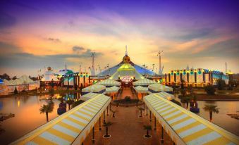 A large building with numerous umbrellas is located at the theme park during dusk or sunset at Carnival City Hotel