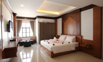 a large bed with white linens and a wooden headboard is in a room with a window and air conditioning at Nonghan Grand Hotel and Resort