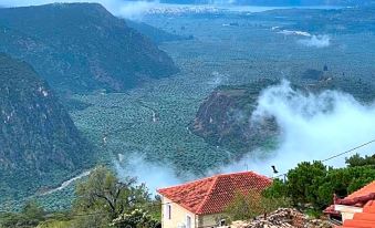 a mountainous landscape with a village nestled in the valley and a red - roofed building on the side of a mountain at Olympic Hotel