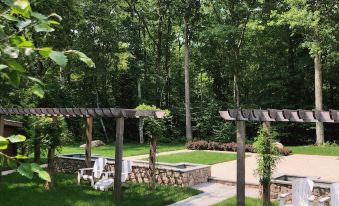 a lush green garden with a wooden pergola and several chairs arranged in a shaded area at Chatfield Hollow Inn
