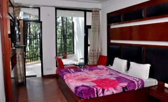 a large bed with a floral comforter is in a room with a wooden headboard and white walls at Hotel Bliss