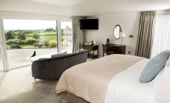 a spacious bedroom with a large bed , a couch , and a tv . the room has a view of a golf course at Peartree Hill
