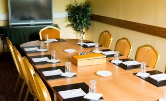 a conference room with a wooden table set for a meeting , surrounded by chairs and a television at Station House Hotel Letterkenny