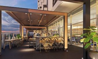 a modern rooftop bar with wooden tables , chairs , and an array of potted plants , under a large glass canopy at Crowne Plaza Hobart, an IHG Hotel