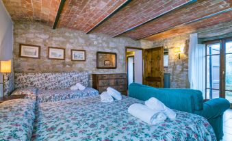 a cozy bedroom with two beds , one of which has a floral bedspread and pillows , and brick walls adorned with artwork at Il Laghetto