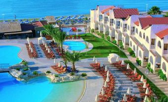 an aerial view of a resort with a large pool surrounded by lounge chairs and umbrellas at Radisson Beach Resort Larnaca