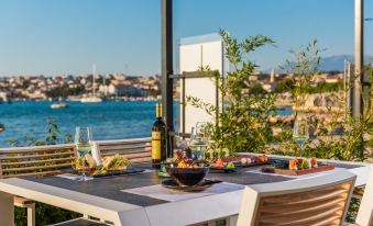 a dining table set with wine glasses , a bowl of food , and a bottle of wine on a patio overlooking a body of water at Liberty Hotel