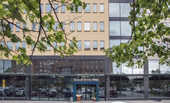 "a modern building with a sign that reads "" bellini hotel "" in front of it , surrounded by trees" at Quality Hotel Winn Haninge
