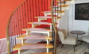 a modern staircase with wooden steps and metal railings , leading to a living room with a white chair at Hotel Zur Post Limburg Bad Camberg