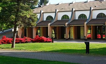 a traditional japanese building with a curved roof and red flowers in front of it at Hotel Pineta