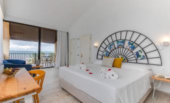 a bedroom with a large bed and a view of the ocean through a window at La Tonnara di Bonagia Resort