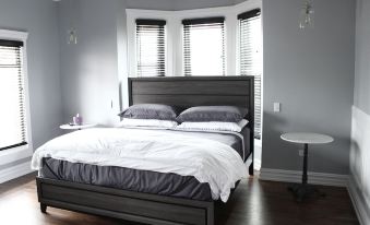 a large bed with a wooden headboard and gray bedding is in a room with white walls and wooden floors at The Plainfield Inn