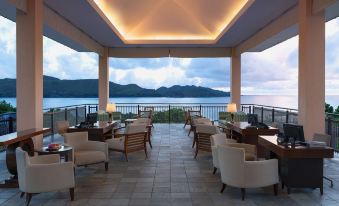 an outdoor dining area with several tables and chairs , surrounded by a beautiful view of the ocean at Raffles Seychelles