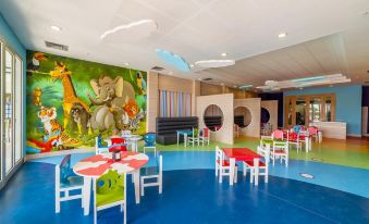 a colorful and playful room with various tables , chairs , and a mural on the wall at Kefaluka Resort