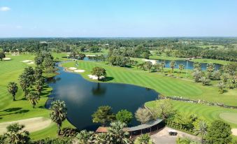 a golf course with a pond in the middle , surrounded by lush green grass and trees at Suwan Golf and Country Club