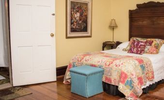 a cozy bedroom with a large bed , wooden floors , and a door leading to another room at Vandiver Inn