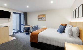 a large bed with a white and brown blanket is in the middle of a room at Oaks Queenstown Shores Resort