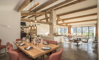 a large , well - lit restaurant with wooden tables and chairs , wine glasses , and a long dining table at Domaine la Pierre Blanche