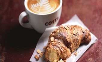 "a croissant and a cup of coffee are placed on a table , with the word "" costa "" written on the cup" at Days Inn by Wyndham Sevenoaks Clacket Lane