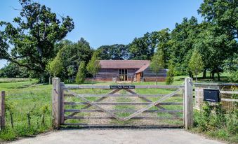 "a wooden gate with a sign that says "" superlane lodge "" is in front of a house" at South Park Farm Barn