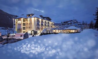 a large hotel surrounded by snow - covered mountains , with a city skyline visible in the background at Majestic Hotel & Spa Resort