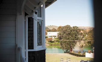 a white house with a large window overlooking a grassy area and a body of water at Cedar House