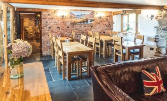 a dining room with wooden tables and chairs , along with a couch and a fireplace at The Wayside and Whisky Barn