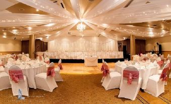 a beautifully decorated banquet hall with white draping , pink tablecloths , and chairs set up for a formal event at Rydges Mackay Suites, an EVT hotel