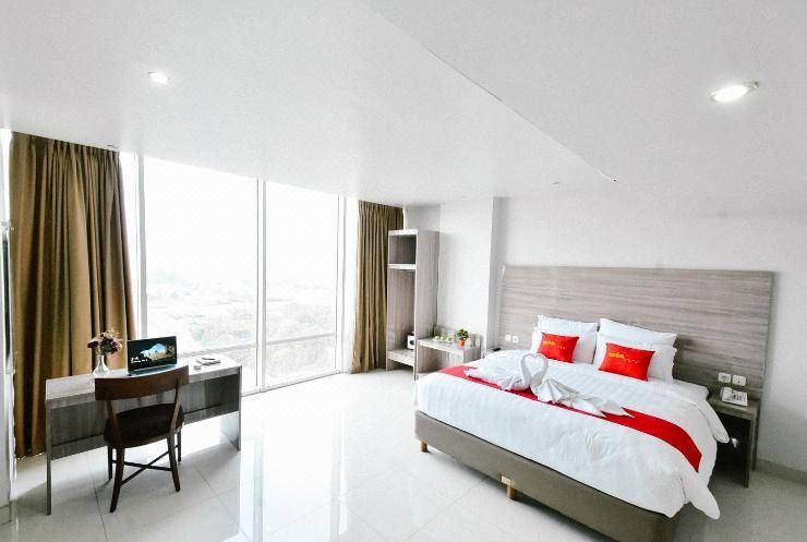 a large , white bedroom with a bed , a desk , and a window overlooking a cityscape at Win Grand Hotel