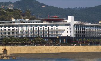 a large white building with a red roof and a helicopter parked on top , overlooking a beach at Grand Hotel Salerno