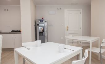 a white dining room with a table and chairs , as well as a refrigerator and vending machine at Los Rosales