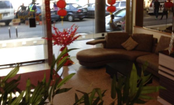 a brown couch is sitting in a room with red lanterns and potted plants on the floor at Royal Hotel