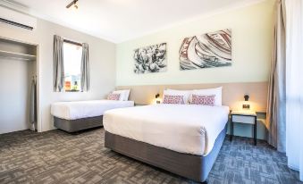 a hotel room with two beds , one on the left and one on the right side of the room at Nightcap at Wanneroo Tavern